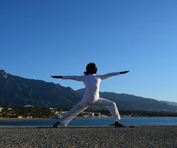 Silhouette of a person in a powerful yoga warrior pose against a sunrise.